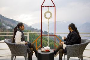 two women sitting in chairs on a balcony at SaffronStays Interstellar in Manāli +34 photos