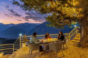 a group of people sitting at a table under a tree at SaffronStays Interstellar in Manāli