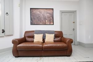 a brown leather couch sitting in a living room at Central Cardiff Victorian Town House Free parking in Cardiff