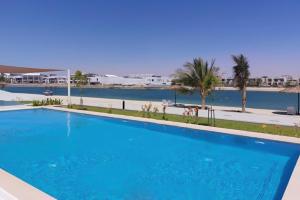 una gran piscina azul junto a un cuerpo de agua en Luxury Villa in Marbella RAK, en Ras al Khaimah