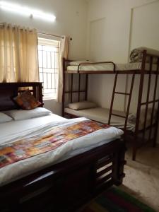 a bedroom with two bunk beds and a window at Kamadhenu Residency Homestay & Service Apartment Coorg Madikeri in Madikeri