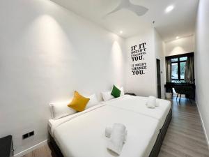 a white bedroom with a large white bed with yellow pillows at The Artz Hotel in Genting Highlands +44 photos
