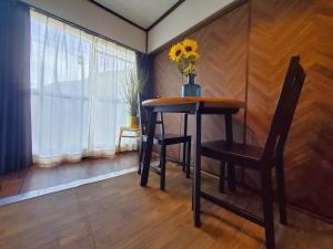 una mesa y una silla con un jarrón de flores. en Route99 Yumoto 箱根湯本駅近山沿い川沿い 箱根湯本徒歩8分WIFI 大人気ゲーム機無料 最大6名 無料駐車場, en Hakone