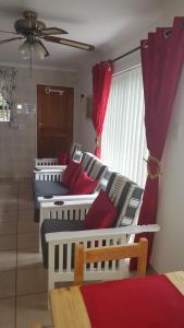 four beds lined up in a room with red curtains at Bayview Selfcatering Apartment in Hartenbos