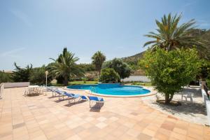 a swimming pool with blue chairs and palm trees at Na Penyal in Cala Millor