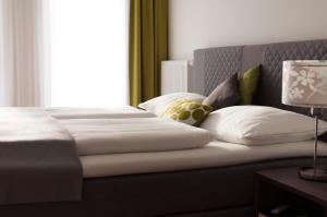 una camera da letto con un letto con cuscini bianchi e una finestra di Ferien am Kurpark a Bad Gleichenberg