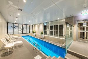 a large swimming pool in a room with chairs and a table at The Heart of City Living with Incredible City & Skytower View Nearby Queen St in Auckland