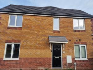 a red brick house with a black door at Entire 3 bedroom luxurious house, Wigan , Manchester in Wigan