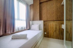a bedroom with a white bed with a window at Minimalist and Comfy 2BR at Titanium Square Apartment By Travelio in Jakarta