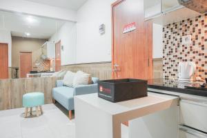 a kitchen and living room with a couch and a table at Minimalist and Comfy 2BR at Titanium Square Apartment By Travelio in Jakarta