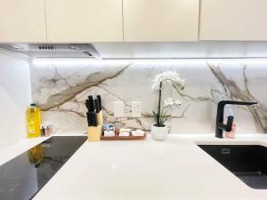 a kitchen with a marble counter top with a sink at Tasteful Luxury Modern 2BR with Aircon in the City Next to Albert Park in Auckland +20 photos