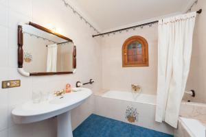 y baño con lavabo, bañera y espejo. en Villa Vallespir, en Puerto de Alcudia