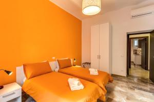 2 łóżka w pokoju z pomarańczowymi ścianami w obiekcie Domus Vita Romana w Rzymie