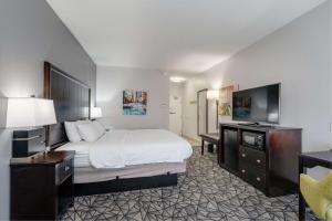 a hotel room with a bed and a flat screen tv at Hampton Inn Bloomington West in Bloomington