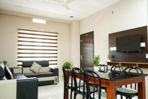 a living room with a couch and a table and chairs at Eagle Nest Residency in Perintalmanna