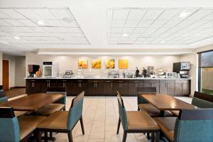 a restaurant with wooden tables and chairs and a kitchen at Comfort Inn & Suites Decatur-Forsyth in Forsyth
