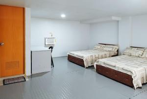 2 letti in una camera bianca con porta di RedDoorz at FJ Hotel Tubungan Iloilo a Tubungan