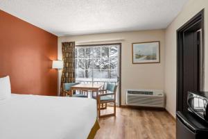 马尼斯蒂Econo Lodge Manistee的一间带床、桌子和窗户的酒店房间