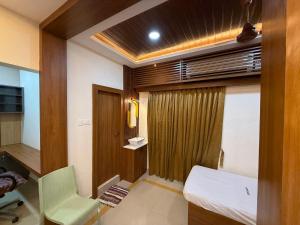 a small room with a bed and a chair at Marudhan Grand in Kumbakonam