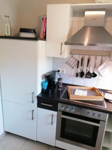a kitchen with white cabinets and a stove top oven at Appartement Auszeit in Olsberg