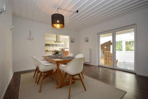 a dining room with a table and white chairs at Ferienhaus-Ankerplatz in Norden