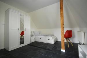 a white room with a bed and two red chairs at Ferienhaus-Ankerplatz in Norden
