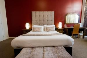 a bedroom with a large bed with a red wall at The Pearl Hotel in Peterborough