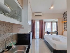 a bathroom with a bed and a sink in a room at Homey and Good Studio Taman Melati Sinduadi Apartment By Travelio in Kejayan +5 photos