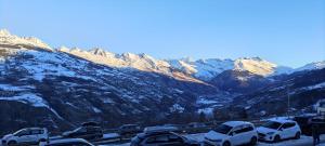 a parking lot with cars parked in front of a mountain at Appartement 5 personnes une chambre proche pistes balcon vue montagne Draps et serviettes non fournis Ménage à réaliser par le locataire in La Plagne Tarentaise +2 photos