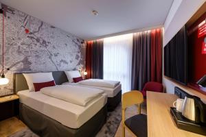 a hotel room with two beds and a table at IntercityHotel Herford in Herford +39 photos