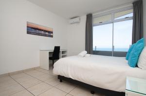 a bedroom with a bed and a desk and a window at 72 Sea Lodge Umhlanga Rocks in Durban