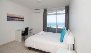 a bedroom with a bed and a desk and a window at 72 Sea Lodge Umhlanga Rocks in Durban