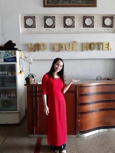 a woman in a red dress standing in front of a hotel at Sao Khue 2 Hotel in Buon Ma Thuot
