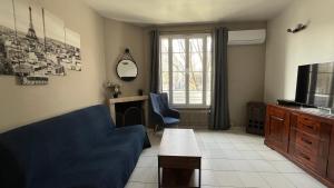 a living room with a blue couch and a tv at Villa Liberté Verdun IGR Paul Brousse in Villejuif