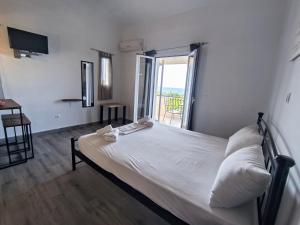 a bedroom with a white bed with a balcony at Aussie Studios in Argostoli