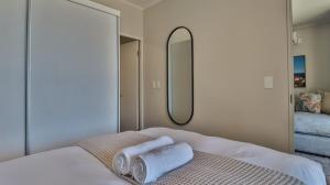 a bedroom with two towels on a bed with a mirror at 105 Mossel Cove Unique & Trendy in Mossel Bay