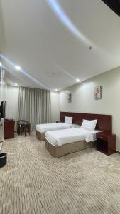 a hotel room with two beds and a television at Kol Alayam Hotel in Mecca