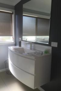 La salle de bains est pourvue d'un grand lavabo blanc et d'un miroir. dans l'établissement Platypus Waters B&B, à Smithton