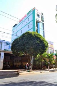 a building with a tree in front of a building at Sao Khue Hotel in Buon Ma Thuot
