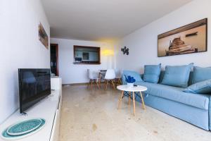 Una sala de estar con un sofá azul y un televisor en PLAYALARGA 2 - Planet Apartment, en Salou