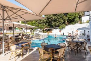 an outdoor patio with tables and chairs and a swimming pool at Apartamentos Alta Galdana in Cala Galdana +10 photos