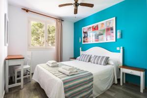 a bedroom with blue walls and a bed with towels on it at Apartamentos Alta Galdana in Cala Galdana