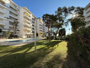 une pelouse avec un parasol devant un bâtiment dans l'établissement Lloret de Mar Coastal Retreat Just Steps from the Beach, à Lloret de Mar