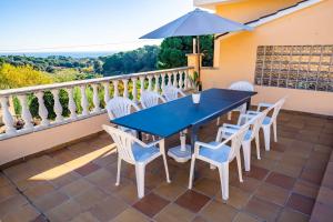una mesa azul y sillas en un balcón con sombrilla en HomeHolidaysRentals Aube, en Sant Cebrià de Vallalta