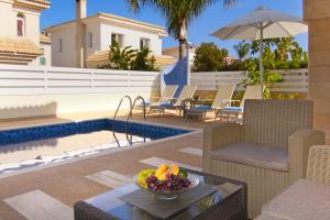 a patio with a table and chairs and a pool at Villa Alyson in Paralimni