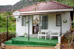 une petite maison blanche avec deux chaises sur une pelouse verte dans l'établissement Wushwini Resort, à Durban