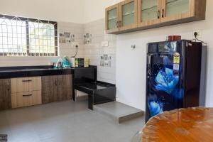 a kitchen with a black refrigerator and a counter at Reunion Charm Villa in Udupi