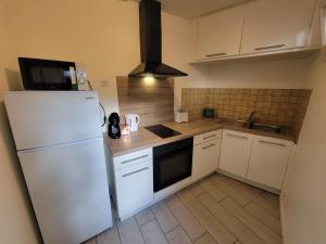 une cuisine avec un réfrigérateur blanc et un évier dans l'établissement Appartement tout équipé avec terrasse à 600m du centre thermal, à Lamalou-les-Bains 13 autres photos