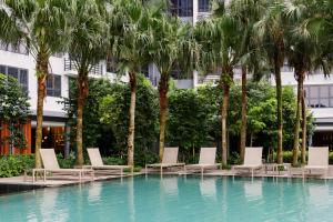 クアラルンプールにあるAgile Bukit Bintang KLCC by DXのヤシの木が茂るスイミングプール(ラウンジチェア付)