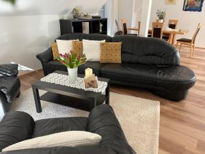 a living room with black leather couches and a table at Apartment Luise in Bad Liebenstein